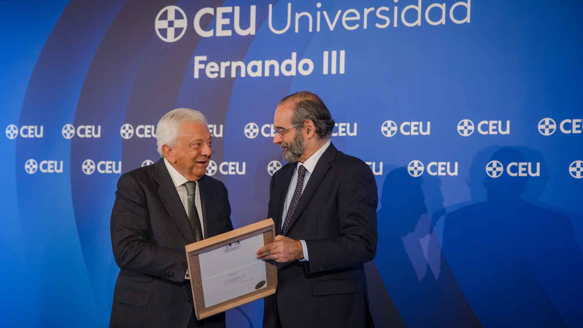 Alfonso Bullón de Mendoza entrega un cuadro enmarcado a Francisco Herrero frente a un photocall azul corporativo en los Premios CEU Fernando III 2026.