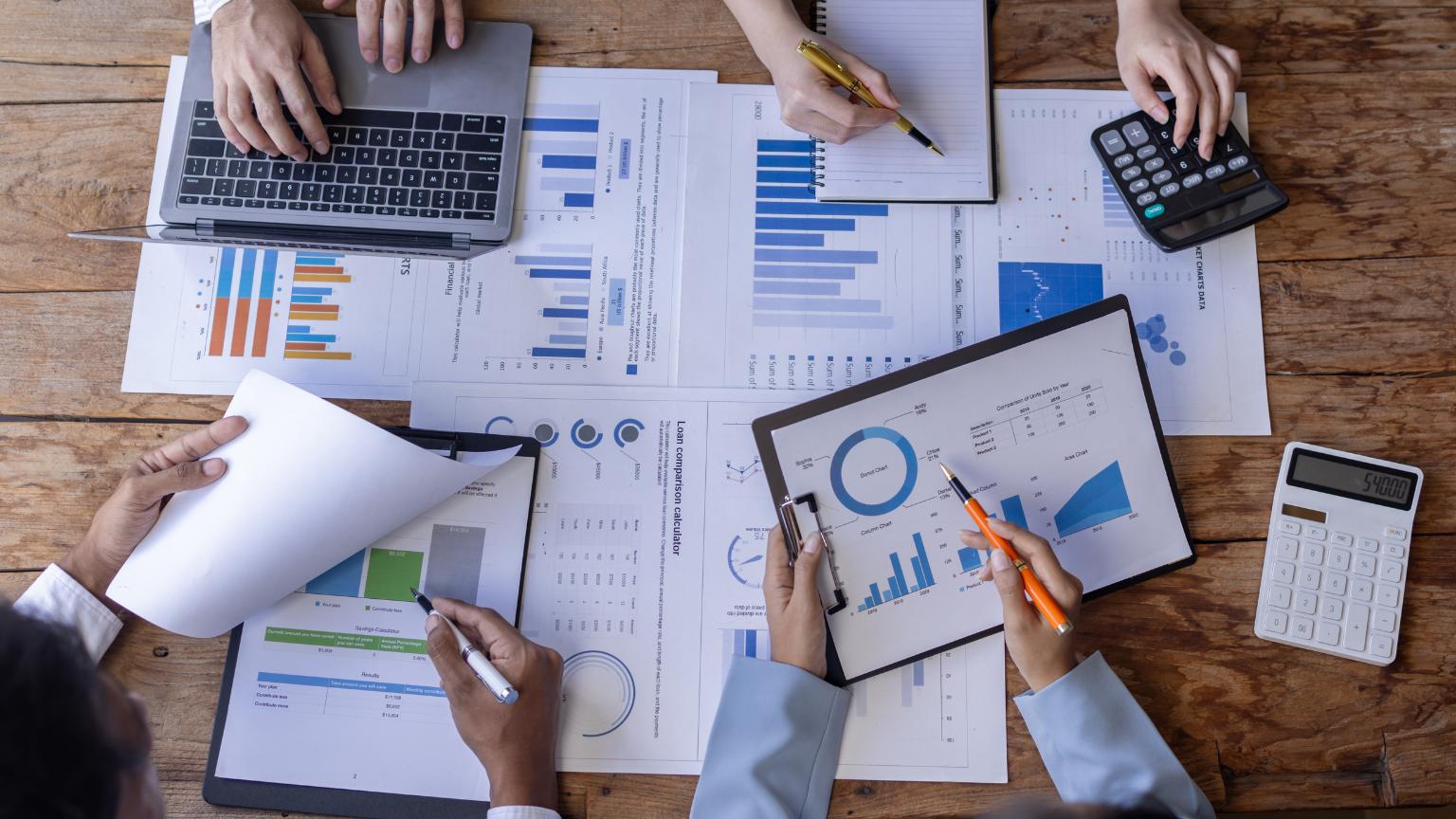 Mesa de trabajo con ordenador, calculadora y gráficas, representando el estudio de Administración y Dirección de Empresas y su proyección profesional.